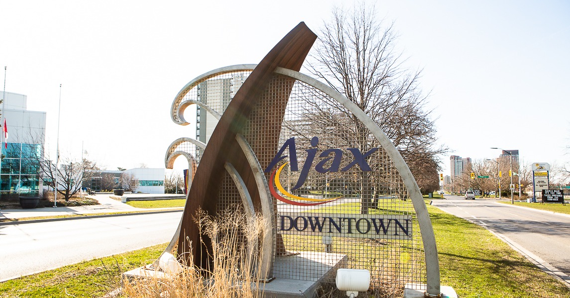 Sculpture sign saying Downtown Ajax, sitting on greenspace