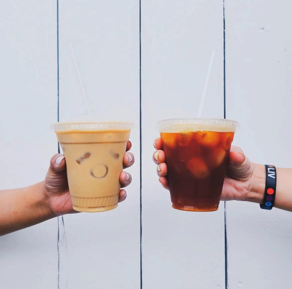 Two people holding iced coffees.