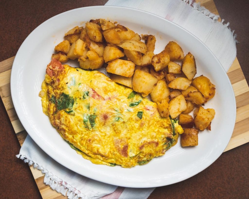 Overhead shot of a huge plate with a Mediterranean omelette and home fries.