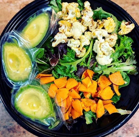 Closeup of salad with avocado, sweet potato, cauliflower, and mixed greens.