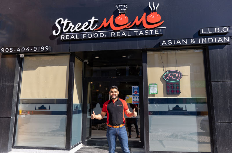 Street Momo owner, Raj, standing in front of restaurant.