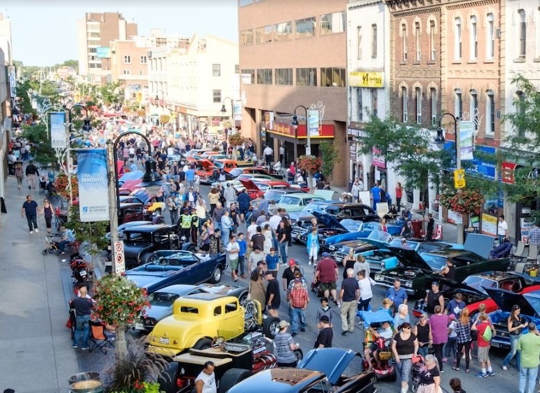 Image of people walking on King street surrounded by vintage automobiles.