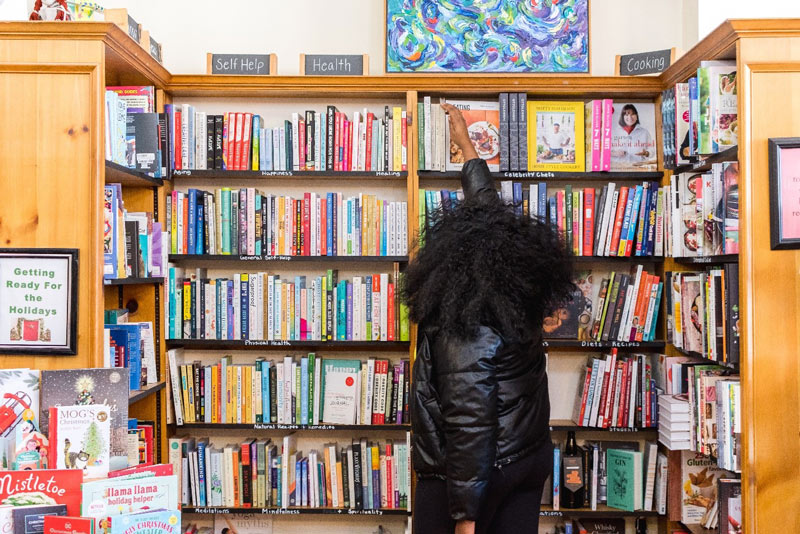 Woman picking a book from a shelf full of books.