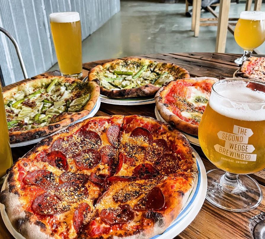 Overhead shot of a table with pizzas from Foundry Pi and craft beers from Second Wedge.