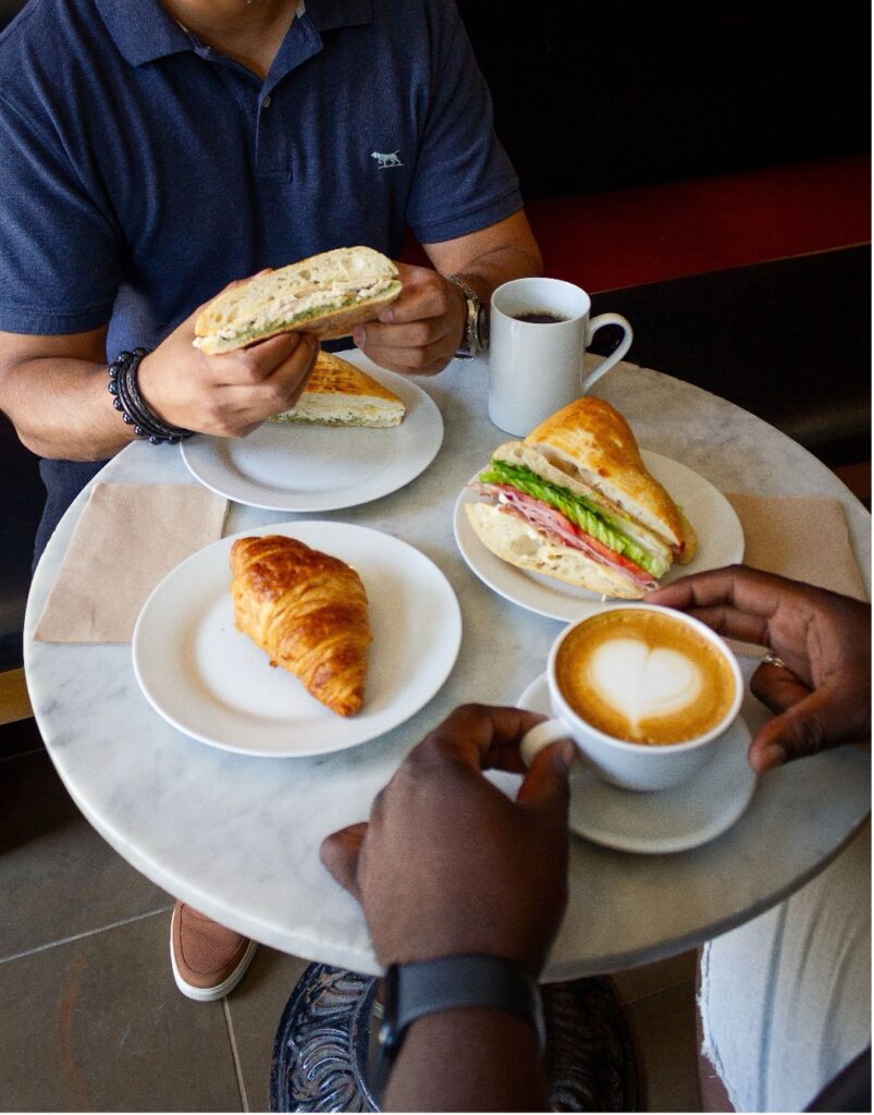 Overhead shot of a table with coffees and sandwiches at Isabella's Chocolate Cafe.