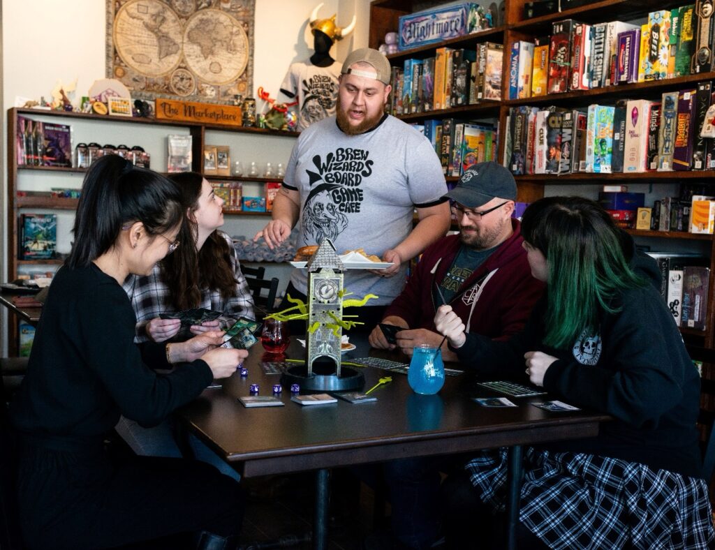 A group of people sitting at a table playing a board game at Brew Wizards in Oshawa.