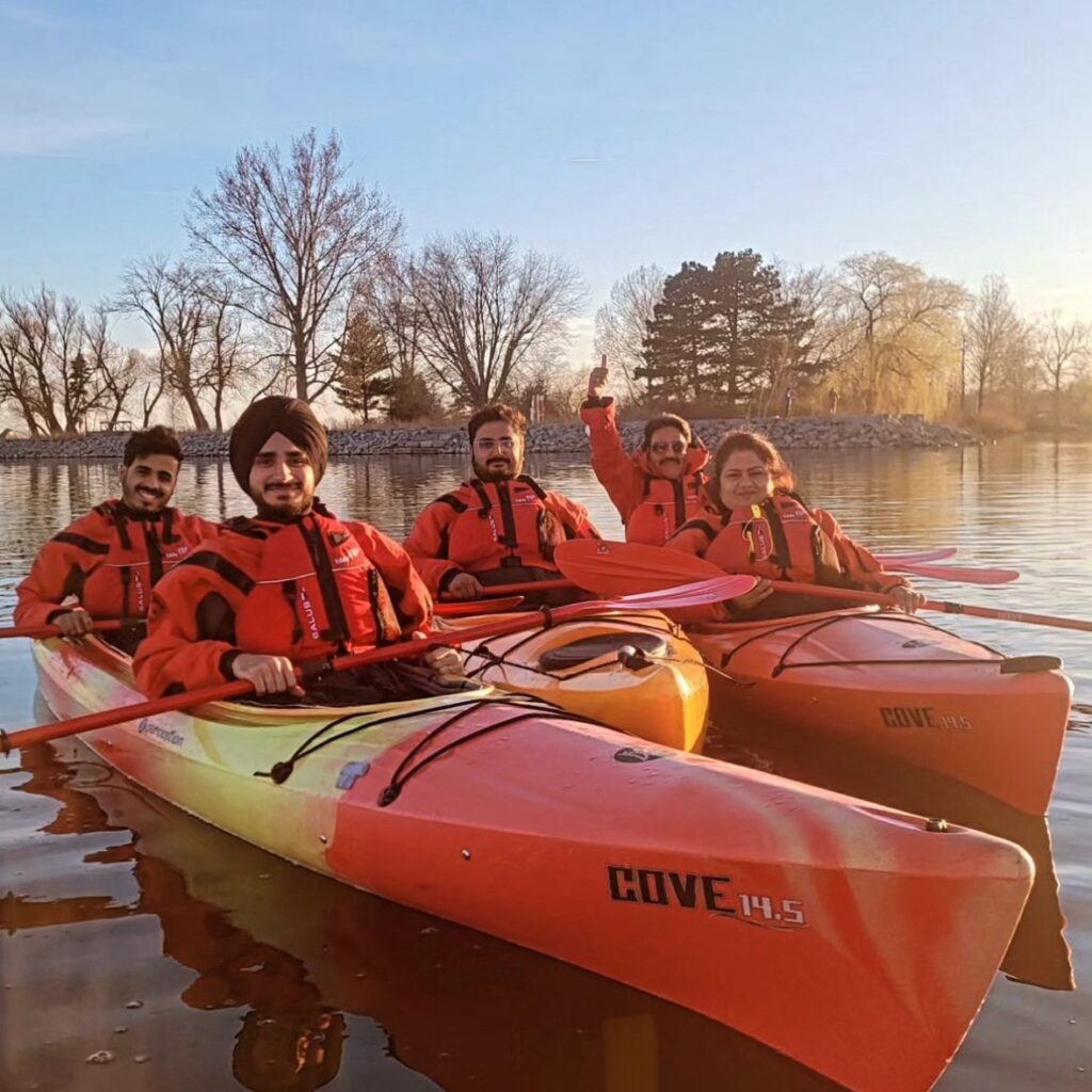 A group of friends sitting in kayaks with life jackets on and smiling for the camera.