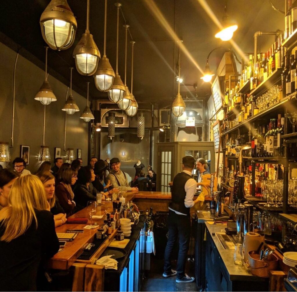 A dimly lit, moody bar crowded with people at the Port Social in Port Perry.