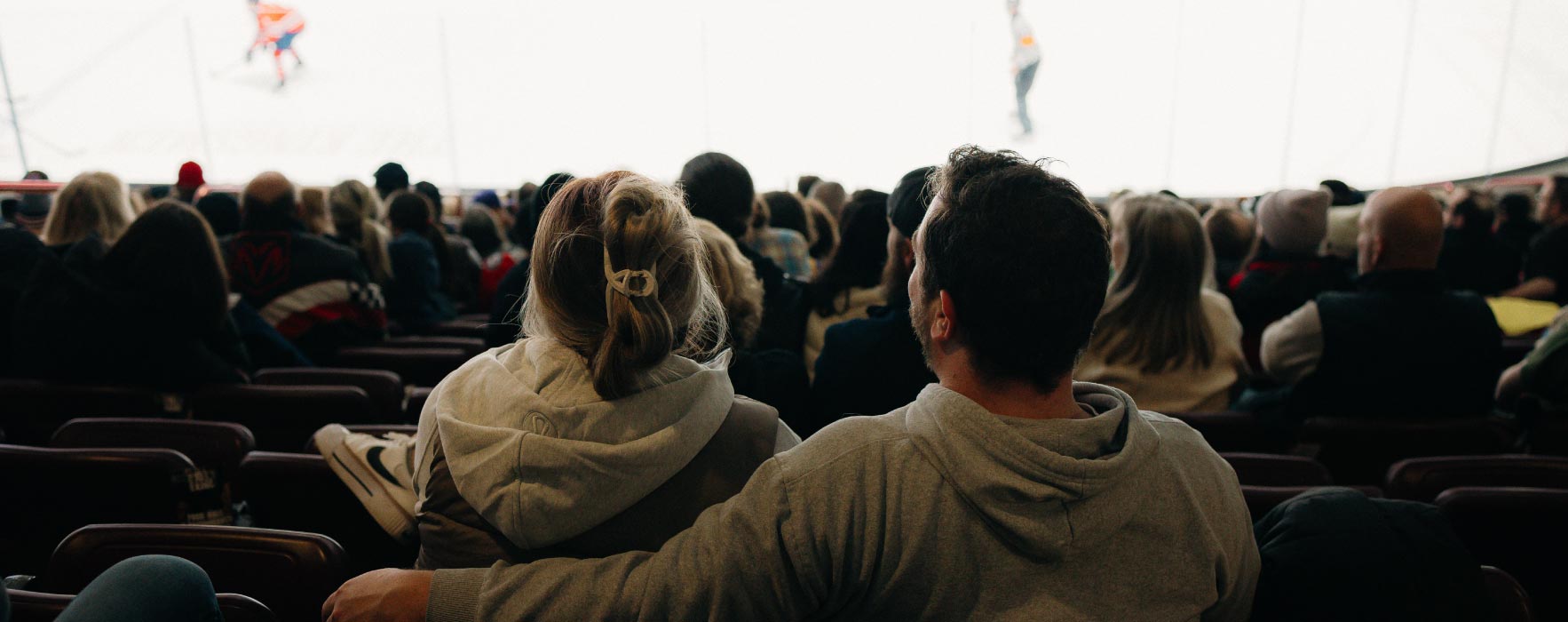 A view from behind a couple sitting in stadium seats watching an Oshawa Generals hockey game.